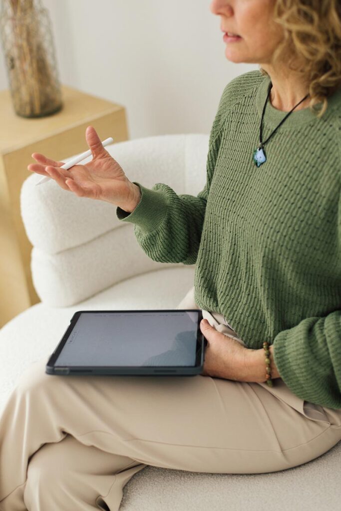 Femme assise, tablette à la main, qui explique les outils du coaching en programmation neurolinguistique (PNL).